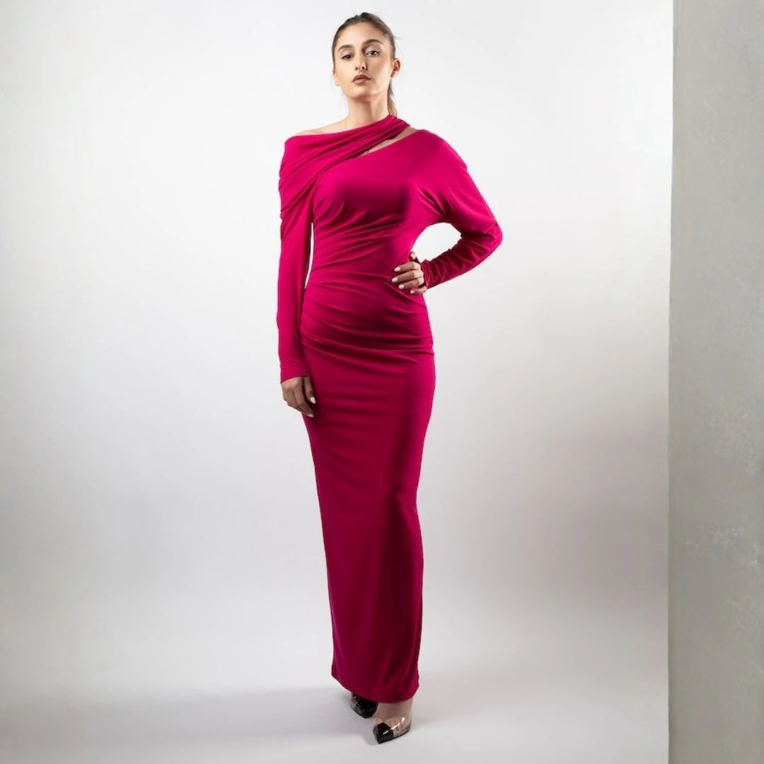 فستان ماكسي بتصميم عصري يبرز القوام، يتميز بفتحة رقبة مبتكرة بكتف مكشوف وتفاصيل ملتفة بأسلوب فني، مع أكمام طويلة وقصة منسدلة 