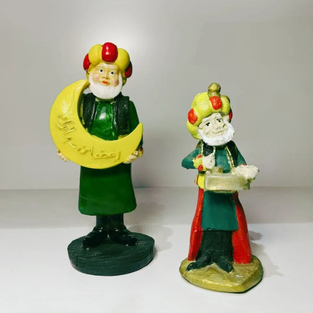 قطعة ديكور رمضانية يجسد شخصية المسحراتي مع طبلة رمضان والهلال بزيّه التقليدي الأخضر والأحمر